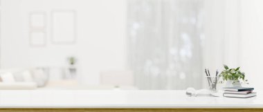 Fotokopi alanı, kitaplar, kırtasiye malzemeleri ve arka planda bulanık beyaz bir oturma odasının üzerinde saksı bitkisi olan modern beyaz bir çalışma alanı. 3d görüntüleme, 3d illüstrasyon