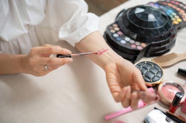 Kolunda ruj izi bırakan, yeni kozmetik ürünler deneyen ve güzellik içeriğini stüdyosunda kaydeden bir kadın güzellik blogcusunun yakın çekim görüntüsü..