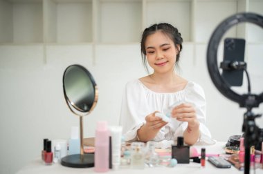 Çekici ve profesyonel bir Asyalı kadın makyaj sanatçısı ya da güzellik uzmanı stüdyosunda güzellik makyajı içeriğini kaydediyor..
