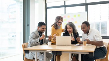 Bir grup neşeli, çeşitli iş adamı ya da girişimciler toplantı odasında heyecanlı bir yüze sahip bir dizüstü bilgisayara bakıyorlar. İyi haber, proje başarısı, kutlama