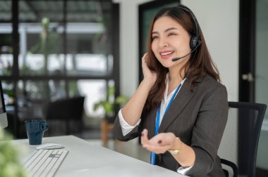 Profesyonel ve çekici bir Asyalı kadın çağrı merkezi operatörü masasında çalışıyor, danışmanlık yapıyor ve arama üzerine olumlu bir müşteri deneyimi sağlıyor. Yardım hattı, tele market.
