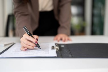 Bir iş kadınının belge ya da sözleşme okurken, masasında kontrat imzalarken yakın plan görüntüsü..