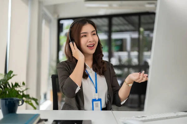 A professional and beautiful Asian female customer support agent is answering incoming calls, explaining, and helping a customer fix their problems online.