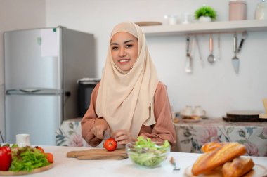 Güzel bir Asyalı Müslüman kadın mutfakta, sağlıklı salata karışımı için malzemeler hazırlıyor. Diyet yemek, ev yemeği, sağlıklı yemek.