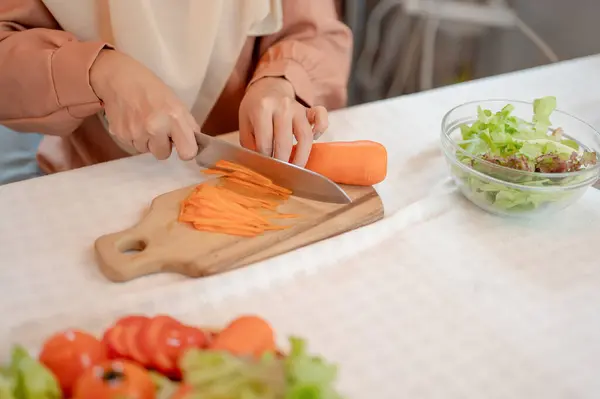 ムスリム女性のクローズアップ画像は キッチンで彼女のサラダミックスのための食材を準備しています チョッピングボード上のナイフでニットをスライス キッチンで料理 — ストック写真