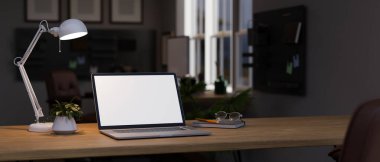 Geceleri ofiste karanlık çalışma alanı, dizüstü bilgisayar beyaz ekran modeli, masa lambası, saksı bitkisi, kitap ve tahta bir masada gözlük. 3d görüntüleme, 3d illüstrasyon