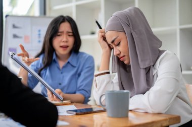 Tatminsiz ve ciddi bir Asyalı iş kadını, projenin hatalarından toplantıda Müslüman çalışanı veya meslektaşına şikayet ediyor..