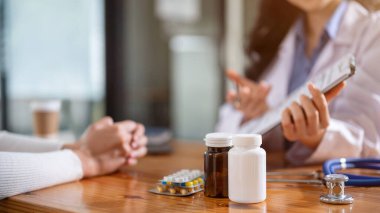 Doktorun muayene odasındaki masada iki şişe ilaç, hap ve steteskopun yakın plan görüntüsü. Sağlık, sağlık kontrolü, sağlık randevusu, teşhis