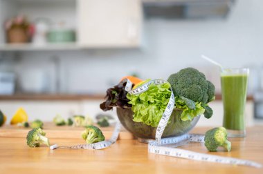 Mutfaktaki mutfak masasında bir kase taze yeşil sebze ve mezura. Görüntüyü yaklaştır. diyet yemeği, beslenme, yeşil salata, sağlıklı yeşil detoks içeceği.