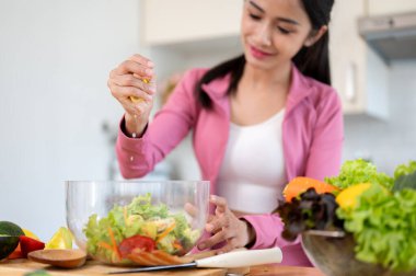 Spor giyimli mutlu ve güzel bir Asyalı kadının yakın plan görüntüsü sağlıklı salata kasesine limon sıkıyor ve mutfakta sağlıklı bir kahvaltı hazırlıyor..