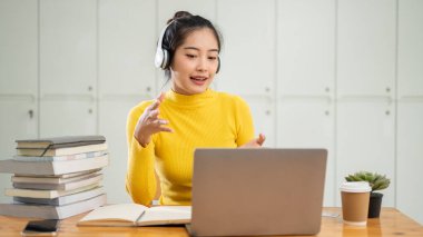 Zeki ve kendinden emin Asyalı genç bir üniversite öğrencisi arkadaşlarıyla çevrimiçi bir toplantı yapıyor. Kütüphanede bir masada otururken internetten ortak bir projeyi tartışıyor..