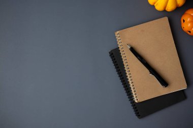 Cadılar Bayramı temalı çalışma alanının en üst görüntüsü. Metinlerinizi, kitaplarınızı, kaleminizi ve küçük balkabaklarınızı gri arka planda göstermek için bir kopya alanı var. düz yat