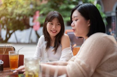 Genç ve güzel bir Asyalı kadın, şehirde açık bir kafede takılırken arkadaşıyla sohbet etmekten zevk alır. Yaşam tarzı ve arkadaşlık kavramları