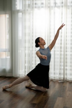 Genç kız modern dairede bale çalışıyor. Genç balerin klasik koreografi pratiği yapıyor. Bale konsepti.