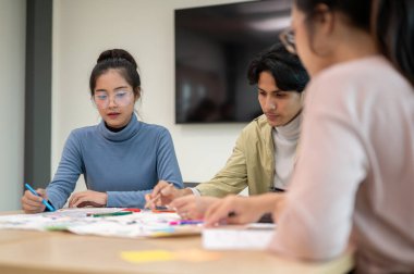 Genç profesyonel UX / UI tasarımcılarından oluşan bir ekip toplantı odasında birlikte çalışarak bir sonraki projeye hazırlanıyor. UX / UI kavramı.