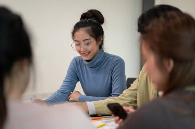 Genç, zeki Asyalı UI / UX tasarımcısı toplantı odasında ekibiyle birlikte proje için çalışıyor. UX / UI kavramı.