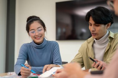 Genç, zeki Asyalı UI / UX tasarımcısı toplantı odasında ekibiyle birlikte proje için çalışıyor. UX / UI kavramı.