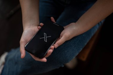 Chiang Mai, Tayland - Ekim 05 2023: Bir kadın evde oturuyor ve Iphone14 aracılığıyla X-Twitter uygulaması kullanıyor. Iphone14 ekranında X-Twitter logosu. Sosyal medya platformu kavramı