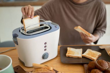 Genç ve güzel bir Asyalı kadının yakın plan görüntüsü mutfakta tost makinesiyle lezzetli tost yapıyor, kahvaltısını hazırlıyor. Yemek pişirme konsepti