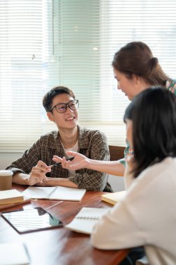 Zeki ve yakışıklı bir Asyalı genç adam toplantı sırasında arkadaşının fikirlerini dinliyor. Üniversite öğrencileri, girişimler, takım çalışması, arkadaşlık