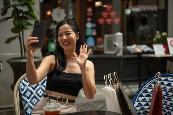 Neşeli ve çekici bir Asyalı kadın kentteki bir kafede ya da restoranda dinlenirken kendi videosunu akıllı telefonuyla çekiyor ya da kaydediyor. Şehir yaşam tarzı konsepti
