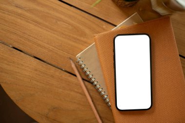Tahta masadaki bir kitabın beyaz ekran akıllı telefon modeli. Çalışma masası, ofis masası, en küçük çalışma alanı üstten görüntü