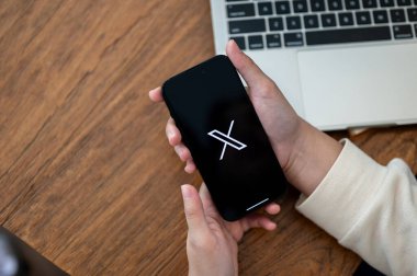 Chiang Mai, Tayland - 18 Ekim 2023: Masasında X Twitter platformunu kullanan bir kadının yakın plan görüntüsü. Sosyal medya platformu kavramı