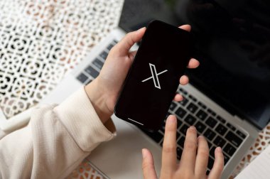 Chiang Mai, Tayland - 19 Ekim 2023: Masasında X-Twitter platformunu kullanan bir kadının yakın plan görüntüsü. Sosyal medya platformu kavramı