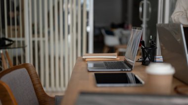 Modern bir toplantı odasında dizüstü bilgisayarlı ve ofis aksesuarlı bir toplantı masasının yan görüntüsü. İş konsepti