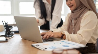 Profesyonel bir Asyalı-Müslüman iş kadınının toplantı odasında meslektaşıyla çalışırken laptopunu kullanırken yakın plan görüntüsü..