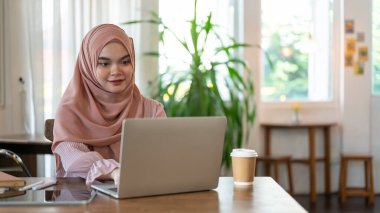 Pembe tesettürlü güzel bir Asyalı-Müslüman kadın, hafta sonları uzaktan bir kafede çalışıyor. İnsanlar ve teknoloji kavramları