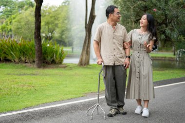 Güzel bir Asyalı kız sabah birlikte yeşil parkta yürürken babasıyla konuşmaktan zevk alıyor. Mutlu aile zamanı konsepti