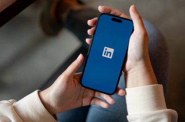 Chiang Mai, Tayland - 31 Ekim 2023: IPhone14 'ünde kapalı otururken LinkedIn kullanan bir kadının yakın plan görüntüsü. IPhone14 ekranında logo bağlantısı var. İş, adam toplama, özgeçmiş, küresel kariyer topluluğu