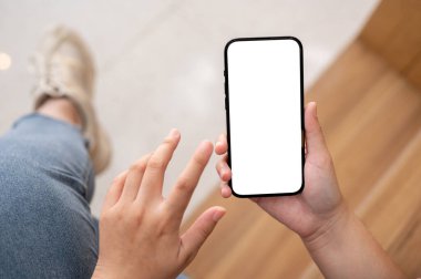 Kafede dinlenirken akıllı telefonunu kullanan bir kadın. Bir kadının elindeki akıllı telefon beyaz ekran maketi. yakın plan resim