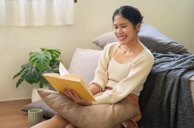 Çekici ve mutlu bir Asyalı kadın hafta sonu yatak odasında dinlenirken kitap ya da roman okumaktan zevk alıyor. Ev hayatı kavramı