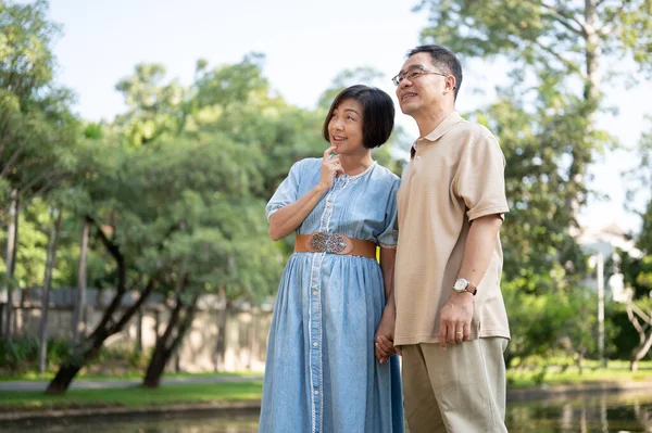 Happy retired senior Asian couples are strolling around a public park on the weekend together. Leisure, happy marriage, healthy relationship