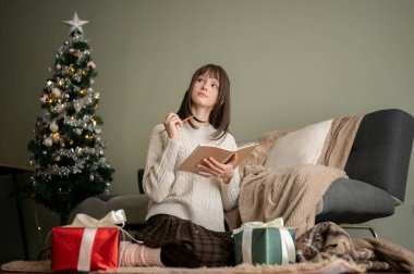 Çekici, sevimli genç bir kadın günlüğünü yazıyor ya da oturma odasında dinlenirken Noel dilek listesi yapıyor, Noel tatilini evde geçiriyor..