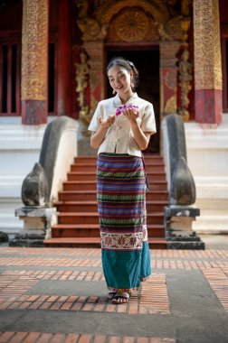 Geleneksel Tayland-Kuzey elbisesi içinde elinde çelenk olan güzel ve çekici bir Taylandlı kadın güzel bir tapınakta. Bir dilek tut, erdem göster, Buda 'ya ve Tayland kültürüne saygı göster.