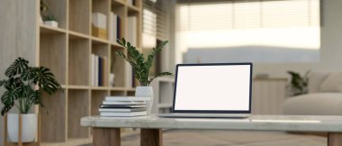 Modern, minimalist bir oturma odasındaki sehpada beyaz ekran dizüstü bilgisayar, kitaplar ve seramik vazo. 3d görüntüleme, 3d illüstrasyon