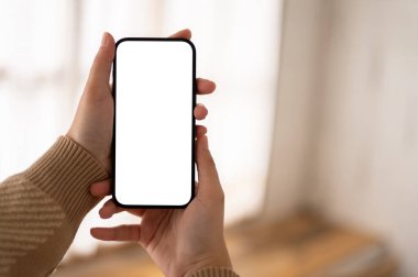 Beyaz ekran akıllı telefon maketini bulanık bir arkaplanda tutan bir kadın. Görüntüyü yaklaştır. İnsanlar ve teknoloji kavramları