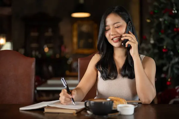 Young rich Asian woman working from home, calling her employee in her luxury vintage home office. Working from home.