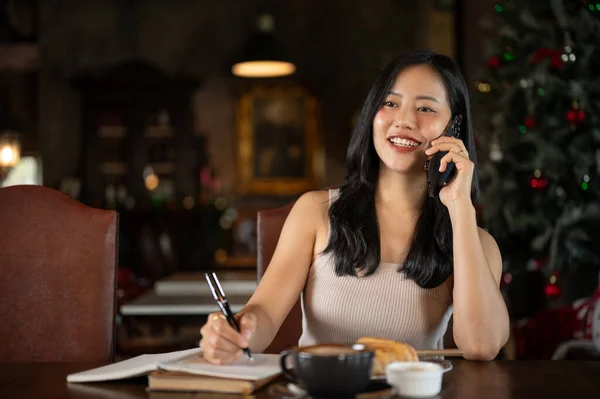 Young rich Asian woman working from home, calling her employee in her luxury vintage home office. Working from home.