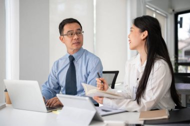 Beyaz, modern ofis odasında kıdemli iş adamıyla çalışan genç bir iş kadını. İş insanları kavramı.