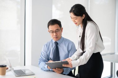 Genç bayan sekreterinin taşıdığı evrakları imzalayan kıdemli işadamı deneyimi. İş konsepti.