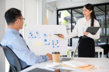 Genç bayan ofis çalışanı iş fikrini toplantı odasında üst düzey yöneticisine sunar. İş planını sunuyorum..