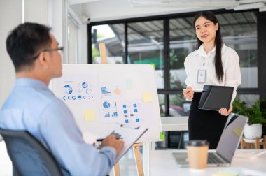 Genç bayan ofis çalışanı iş fikrini toplantı odasında üst düzey yöneticisine sunar. İş planını sunuyorum..