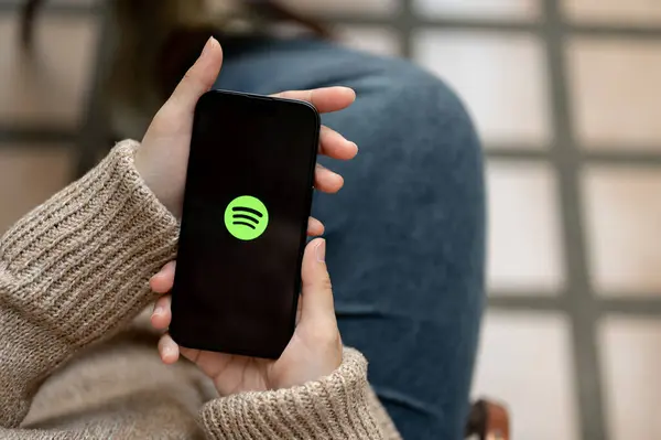 Chiang Mai, Tayland - 21 Kasım 2023: Açık havada otururken Spotify uygulamasını kullanan bir kadının yakın plan görüntüsü. IPhone14 ekranındaki logoyu bozun. Müzik uygulaması