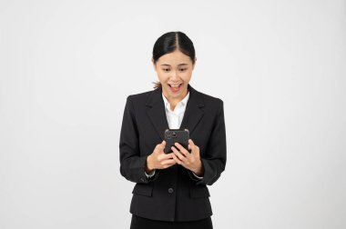 Genç, neşeli Asyalı iş kadını elinde akıllı telefonuyla iyi haberlerle kutlama yapıyor..