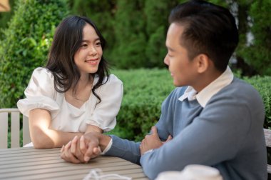 Genç ve sevimli Asyalı çift parkta birlikte vakit geçiriyorlar, birbirlerine yakın oturuyorlar. Takılıyorum.