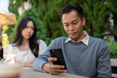 Genç Asyalı kız arkadaşı ona dikkat etmediği için erkek arkadaşına kızıyor. çift kavramı.